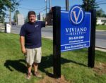 DMS Sign Connection, Inc. installer Dean stands next to Viviano Realty Post and Panel Sign