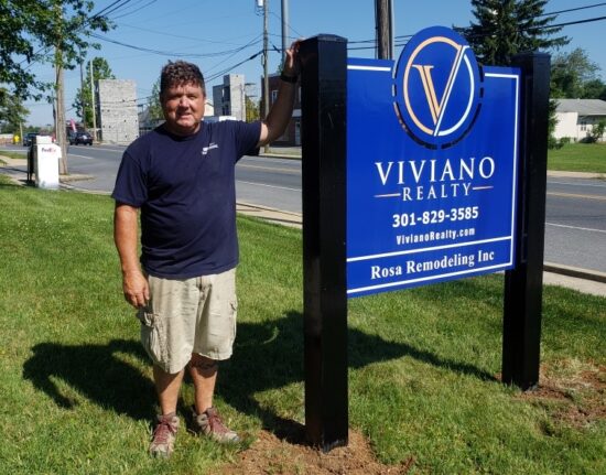 DMS Sign connection installer stands next to Viviano Realty Post and Panel Sign